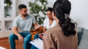 A young couple actively participates in a pre-conception counselling for couples with their gynaecologist at a women's health clinic.