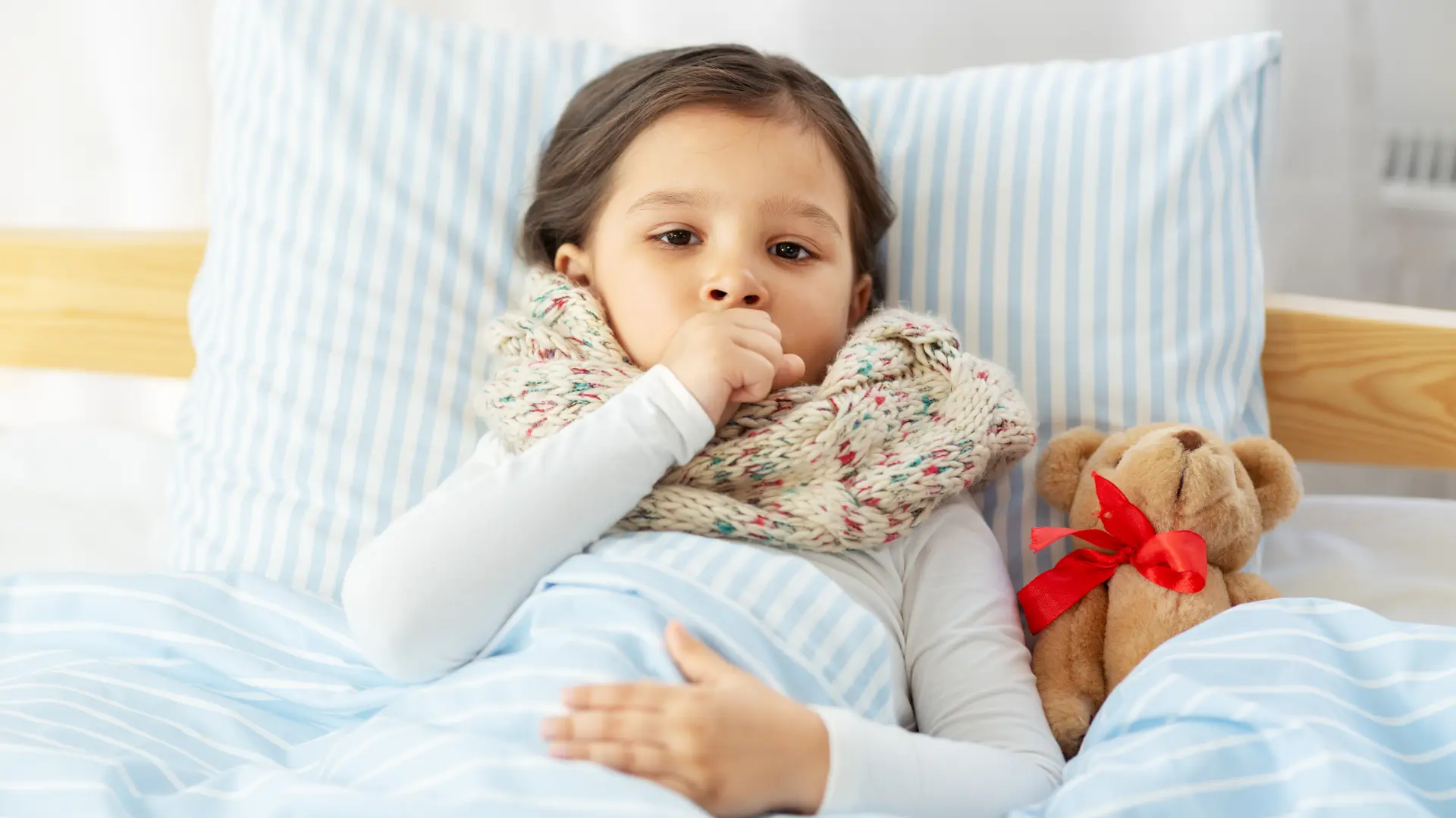 A young child wrapped in a blanket sipping a warm, natural remedies for cold and cough.