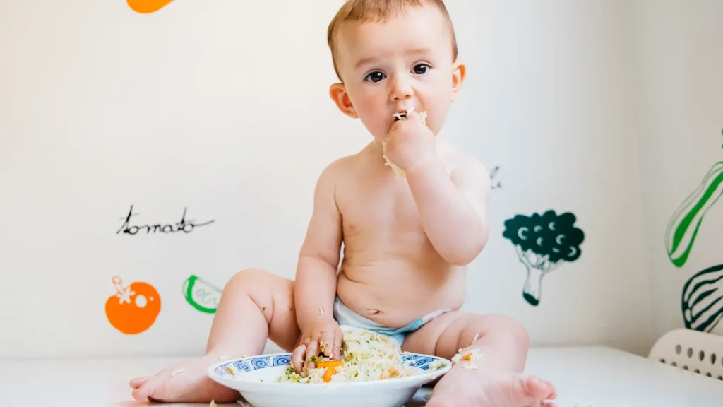 A happy baby enjoys their first taste of solid food that is child nutrition.